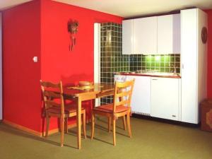 a kitchen with a table and chairs and a red wall at Apartment Pony 2-Bettwohnung by Interhome in Lenk