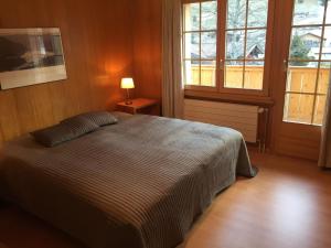 a bedroom with a bed and a lamp and windows at Apartment Butterfly by Interhome in Adelboden