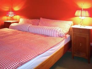 a bedroom with a bed with red walls and two lamps at Apartment Pony 2-Bettwohnung by Interhome in Lenk