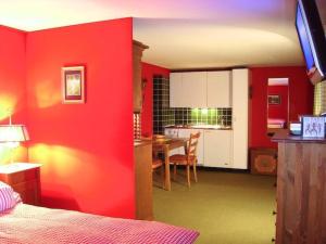 レンクにあるApartment Pony 2-Bettwohnung by Interhomeの赤い壁のベッドルーム、キッチン(テーブル付)