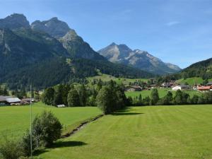 ein grünes Feld mit Bäumen und Bergen im Hintergrund in der Unterkunft Apartment Sonnegg by Interhome in Gsteig