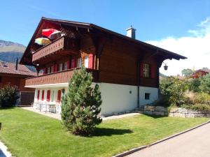 a large wooden house with a tree in front of it at Apartment Bärnermutz # 1 by Interhome in Lenk