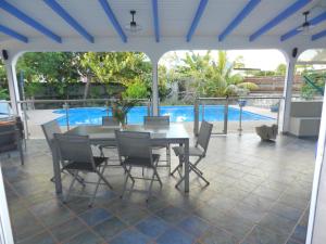 a patio with a table and chairs and a pool at VILLA LE BORD BLEU in Le Moule