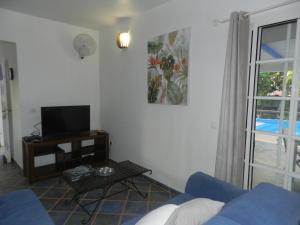 un salon avec un canapé bleu et une télévision dans l'établissement VILLA LE BORD BLEU, à Le Moule