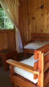 Cabaña de madera con 2 camas y ventana en Cabañas Trabunco, en Pucón