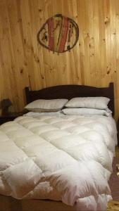 Cabañas Trabunco في بوكون: سرير أبيض كبير في غرفة بجدران خشبية