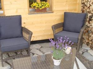 2 Stühle und ein Tisch mit Blumen auf der Terrasse in der Unterkunft Apartment Gwunderstübli by Interhome in Lenk im Simmental