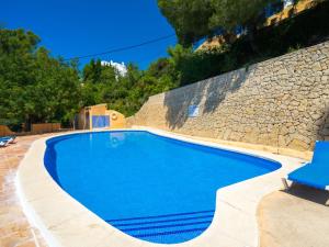 a swimming pool next to a stone wall at Apartment Miramar by Interhome in Moraira