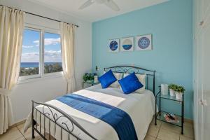 Un dormitorio con una cama con sábanas azules y blancas y una ventana en 207 Kings Palace Seaview en Pafos