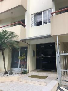 una casa con una palmera delante de ella en Lindo apartamento super completo em Meia Praia, 100 metros do mar e 10 quadras do centro, en Itapema