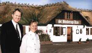 um homem e uma mulher em pé em frente a um edifício em St. Binderup Kro em Store Binderup