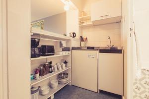 Elle comprend une petite cuisine avec un réfrigérateur et des étagères. dans l'établissement La Maison de la Liberté Studio Jules Verne, à Poitiers