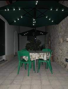a green table and chairs under a black umbrella at Hedera Capri B&B in Anacapri