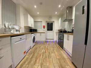 a kitchen with white cabinets and a wooden floor at Heaton Park Road Professional Lets in Newcastle upon Tyne