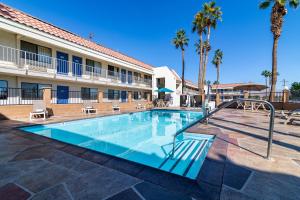 een zwembad tegenover een hotel met palmbomen bij Rodeway Inn & Suites Thousand Palms - Rancho Mirage in Thousand Palms