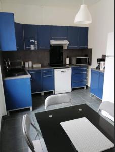 une cuisine avec des armoires bleues, une table et des chaises dans l'établissement Bel appartement ancien Poitiers Centre - 4 Chambres, à Poitiers