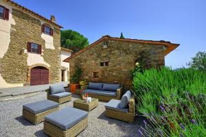 un patio con divani e sedie di fronte a un edificio di Villa Uccellaia by PosarelliVillas ad Agello