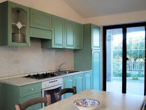 een keuken met groene kasten en een tafel met een kom erop bij LE MAREE I LENTISCHI in San Teodoro