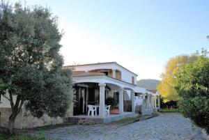een wit huis met twee witte stoelen op de veranda bij LE MAREE I LENTISCHI in San Teodoro +7 foto's