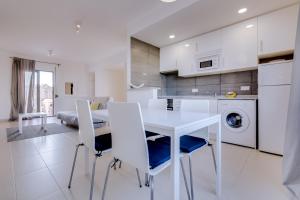a white kitchen with a white table and chairs at Cruzeiro do Sul Apartments - Vilamoura center in Vilamoura