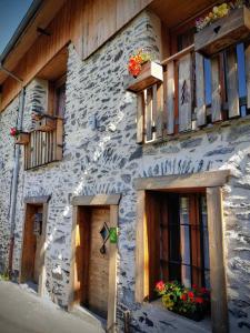 un edificio de piedra con ventanas y flores. en Cosy Lodge au pied de l'Alpe D'Huez SKi et Détente Jacuzzi Piscine Sauna Bar Billard, en Le Bourg-dʼOisans