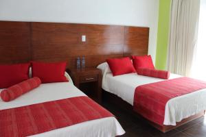 a hotel room with two beds with red pillows at Hotel Real Tamasopo in Tamasopo