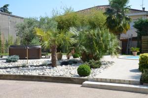 a garden with palm trees and rocks at Chambre D'hôtes Et Spa in Agen