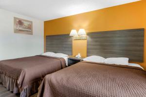 two beds in a hotel room with yellow walls at Riverside Inn & Suites in Riverside