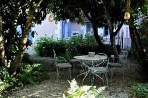 a table and chairs in a garden with trees at Le Vieux Saule in Saints