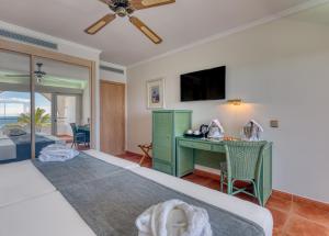 a bedroom with a bed and a desk with a television at Playacálida in Almuñécar