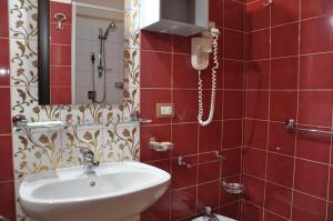 a red tiled bathroom with a sink and a shower at Regalpetra Hotel in Racalmuto +85 photos