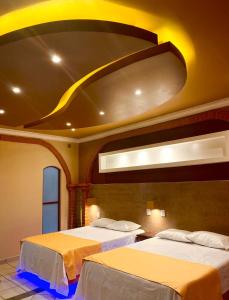 twee bedden in een kamer met een groot plafond bij Hotel Boutique TEKALI INN in Cuetzalán del Progreso