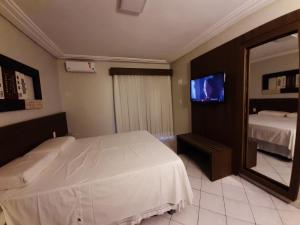 1 dormitorio con cama blanca y espejo en Hotel Asa Branca en Belo Jardim