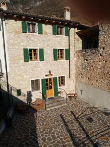 ein Steingebäude mit grünen Rollläden und einer gelben Tür in der Unterkunft Ca' del Laki in Caprino Veronese