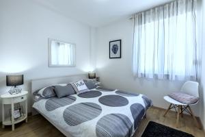 a bedroom with a bed and a chair and a window at Iris beach apartments in Kaštela