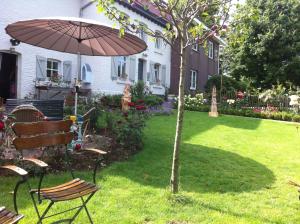 a garden with a chair and an umbrella and a tree at PuurTeuven B&B tussen Kunst en Natuur in Voeren