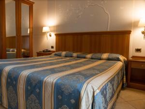 a hotel room with a bed with a blue blanket at Dipendenza Hotel Londra in Alessandria