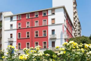 um edifício vermelho e branco com flores amarelas em Dipendenza Hotel Londra em Alessandria