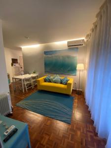 un sofá amarillo en una sala de estar con mesa en AP da Baixa, en Oporto