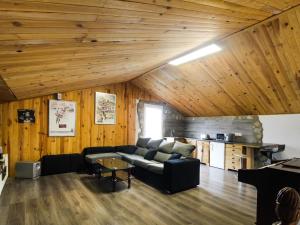 una sala de estar con sofá negro y techos de madera. en Belvilla by OYO La Casa de Valen, en Villamuriel de Cerrato