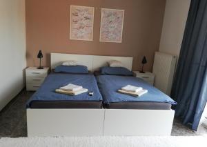 a bedroom with two beds with blue sheets and towels at TIFFANY Apartman in Jenő