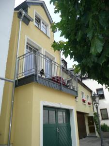 a yellow house with a green door and a balcony at Mosel Ferienhaus Bernkastel in Bernkastel-Kues