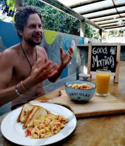 un hombre sentado en una mesa con un plato de comida en Freesoul Hostel, en Palomino