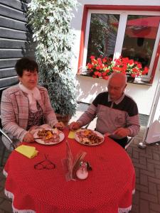 um homem e uma mulher sentados numa mesa com pratos de comida em Harzbaude - Pension Gasthaus Bodetal em Rübeland