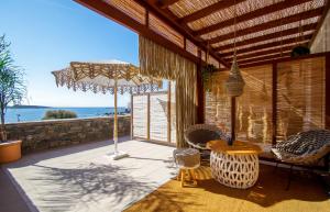 un patio con mesa, sillas y sombrilla en Syros Wellness Luxury Suites, en Finikas