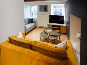 een woonkamer met een gele bank en een tafel bij Superb holiday home in the centre of Aywaille in Aywaille