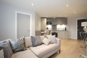 a living room with a couch and a kitchen at Foundry luxury new one bedroom apartments close to town center in Luton