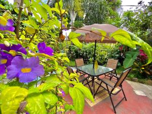 a table and chairs with an umbrella and flowers at Vila Pequeá Ilhabela in Ilhabela