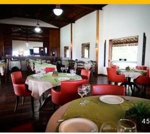 uma sala de jantar com mesas e cadeiras vermelhas com copos em Flat Fazenda Monte Castelo Gravatá em Gravatá