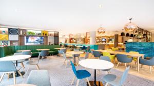 a restaurant with tables and chairs and a bar at Holiday Inn London Luton Airport, an IHG Hotel in Luton